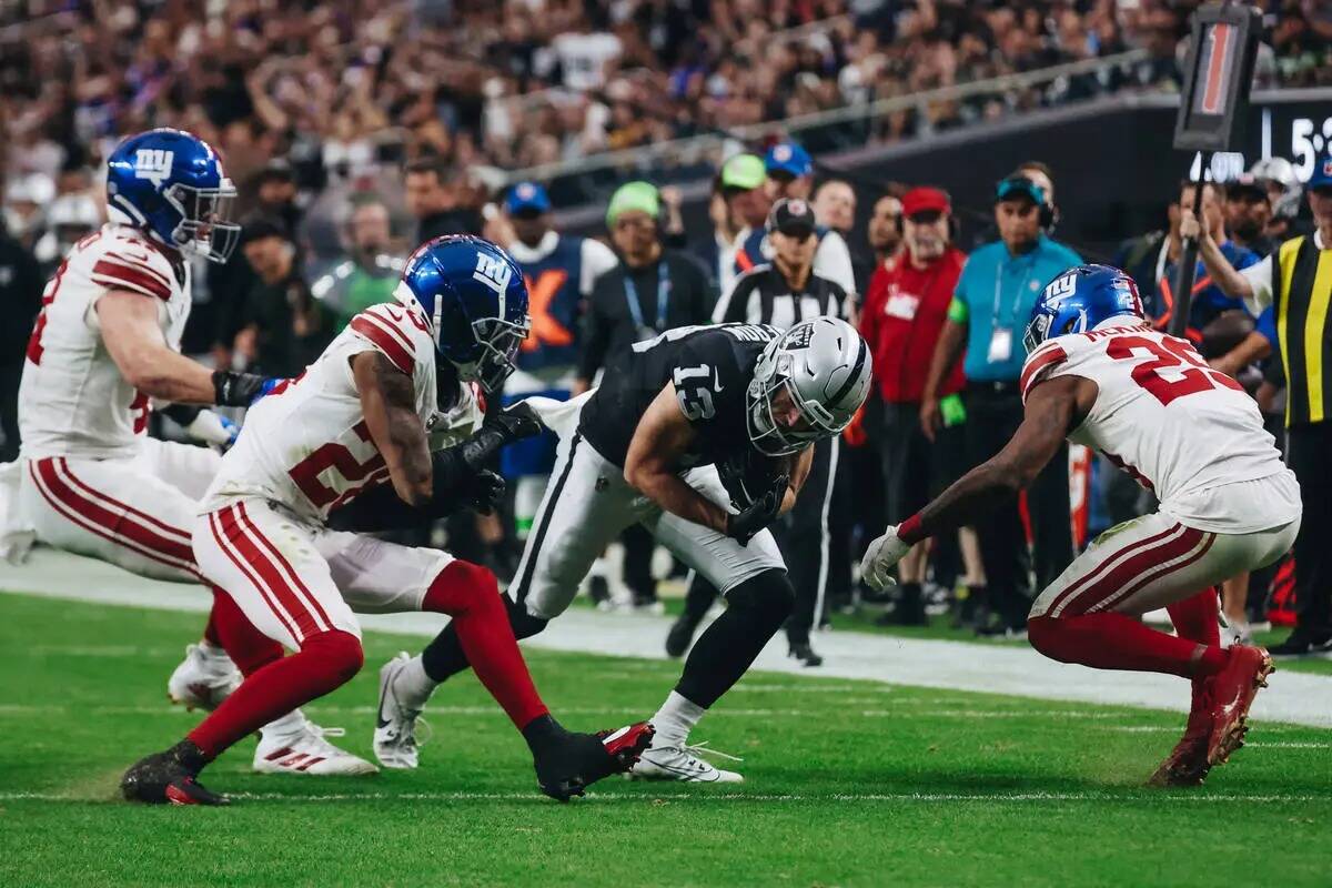 El wide receiver de los Raiders Hunter Renfrow (13) se aferra al balón mientras los defensas d ...