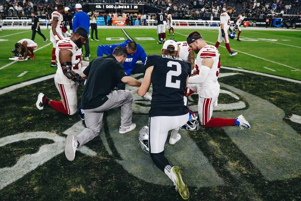 El pateador de los Raiders Daniel Carlson (2) reza con los jugadores y el cuerpo técnico de lo ...