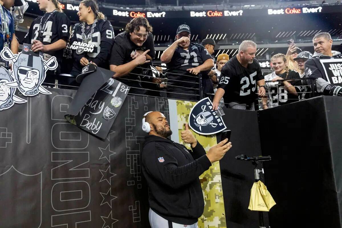 El tackle ofensivo de los Raiders Jermaine Eluemunor (72) se toma una selfie con los fans antes ...