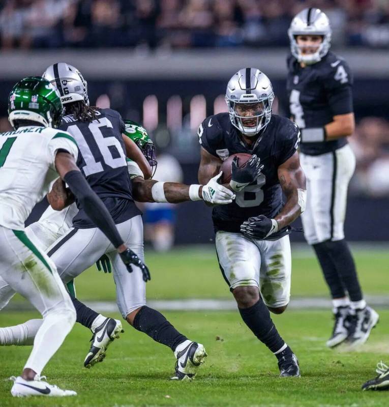 El running back de los Raiders Josh Jacobs (8) atraviesa la fila en busca de más yardas contra ...