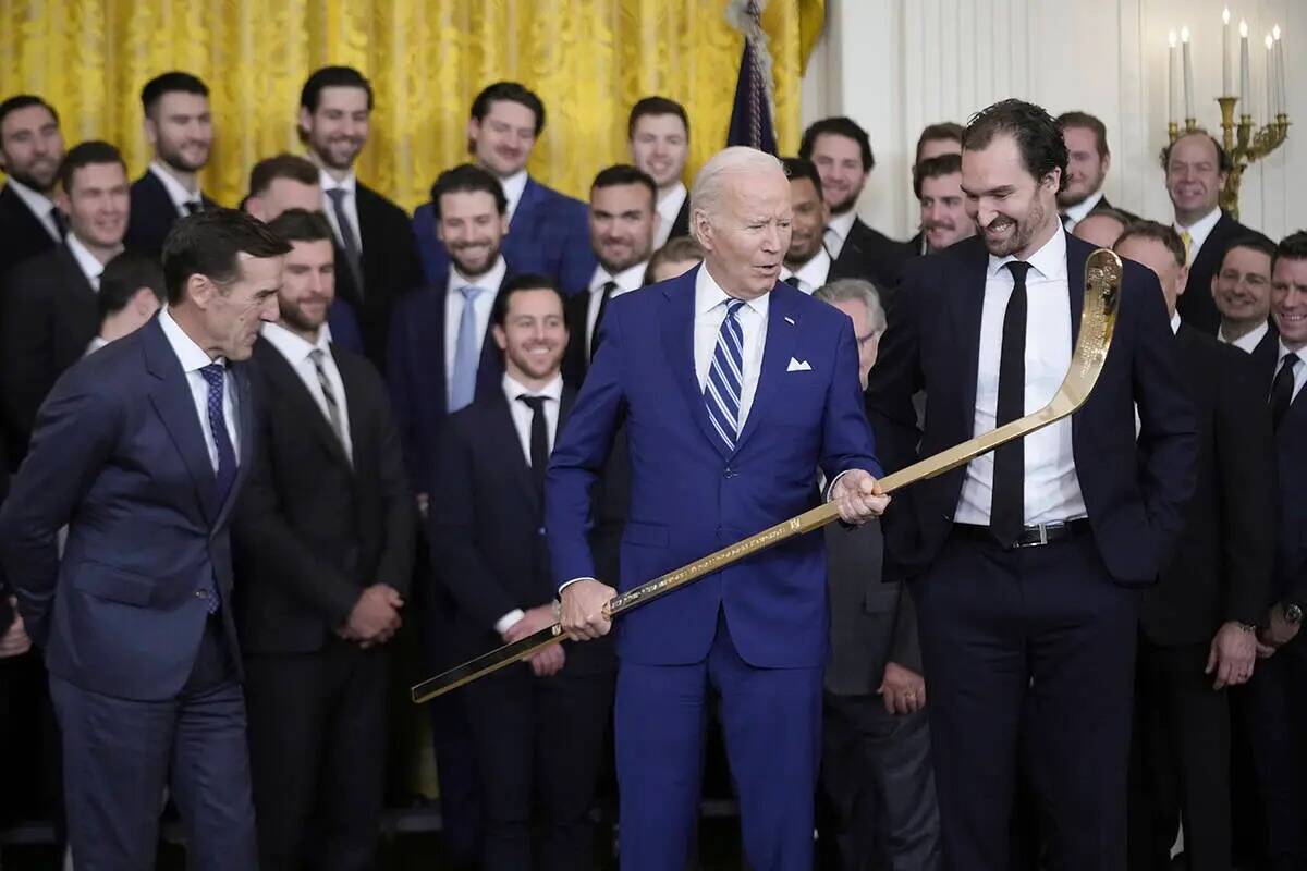 El presidente Joe Biden observa un bastón de hockey durante un evento para celebrar la victori ...