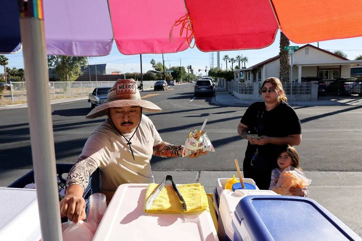 El vendedor ambulante Luis Serrano atiende a Leslie Ortega y a su hija Grace, de 4 años, en el ...