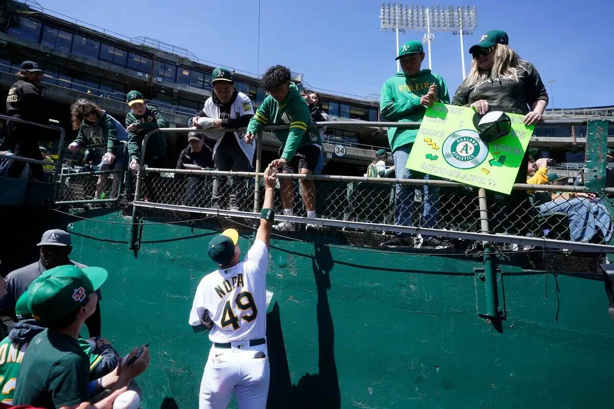 Ryan Noda, de los Oakland A's, firma autógrafos para los fans antes de un partido de béisbol ...