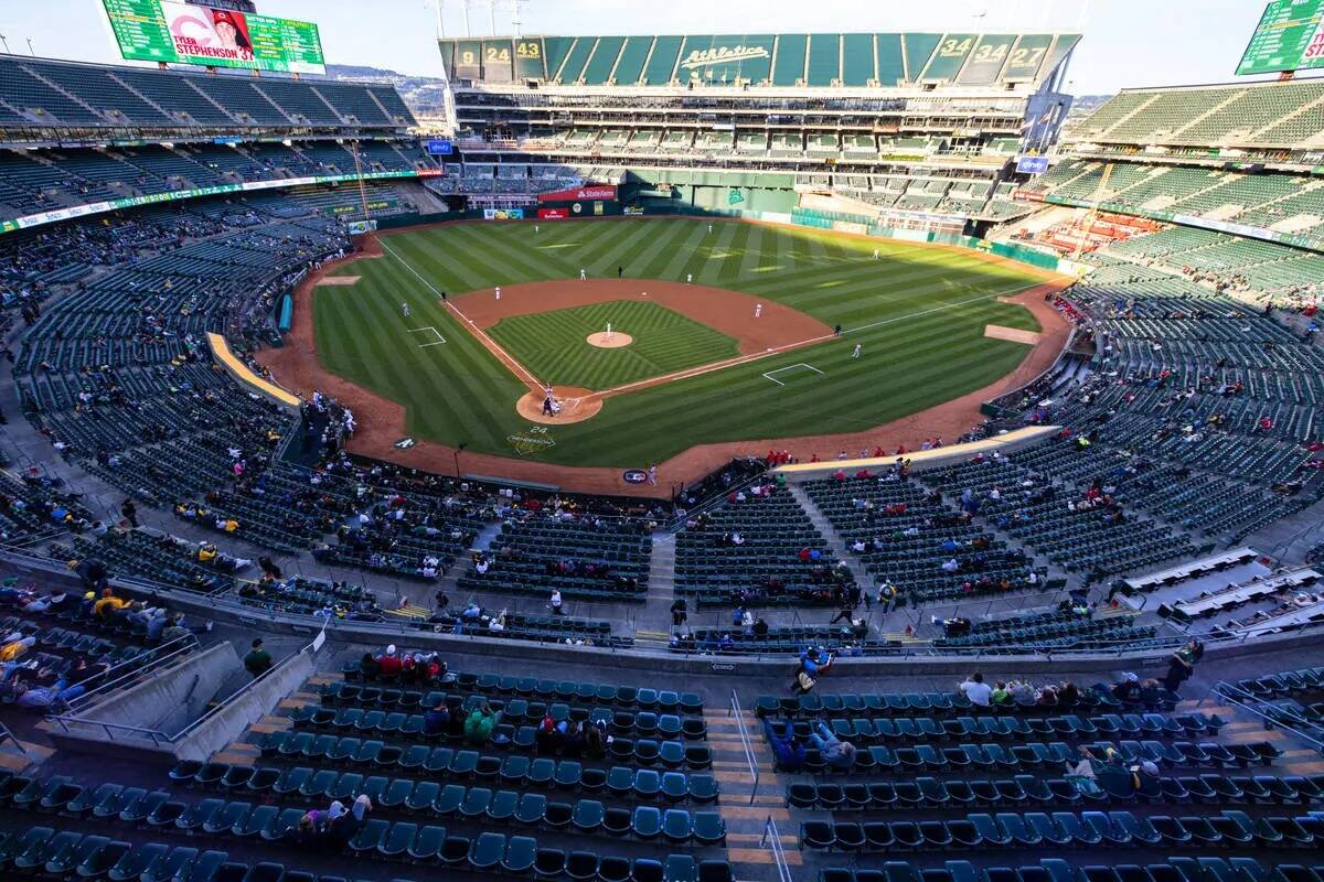 Los fans ven un partido de béisbol entre los A's y los Cincinnati Reds en el Oakland Coliseum, ...