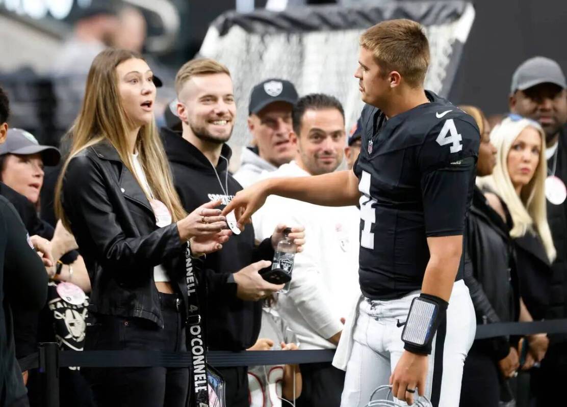 El quarterback de los Raiders Aidan O'Connell (4) charla con su esposa Jael mientras sale al ca ...