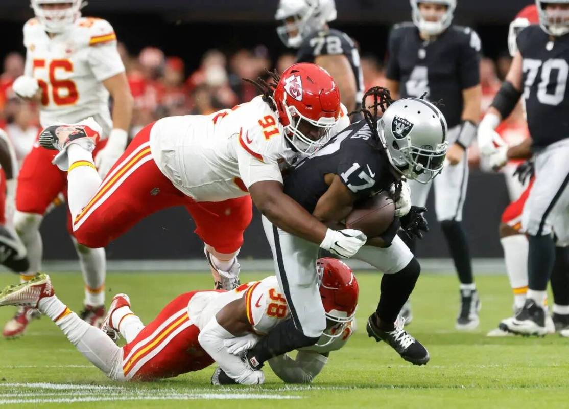 El wide receiver de los Raiders Davante Adams (17) es derribado por la tacleada defensiva de lo ...