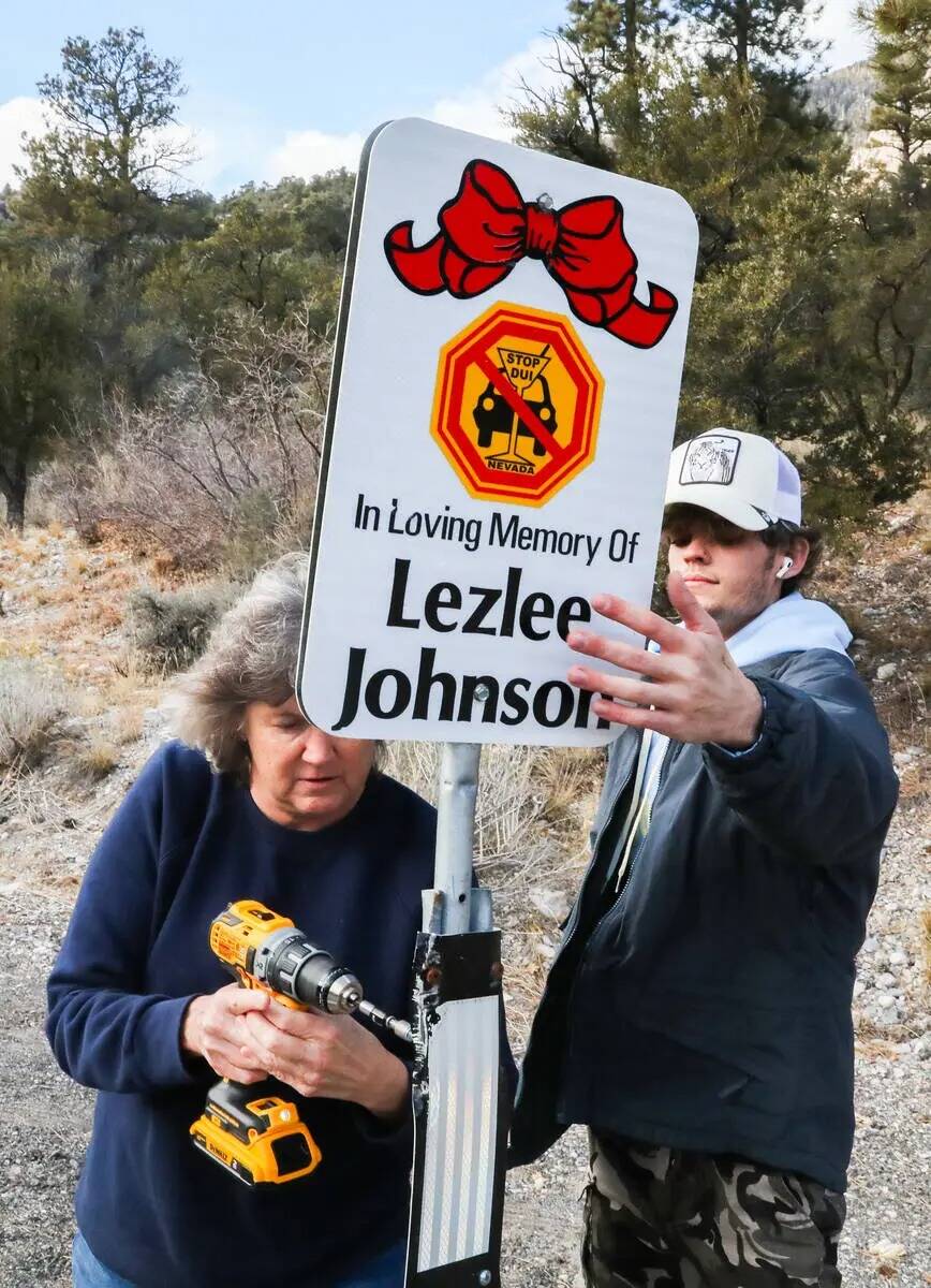 Bonnie Heverly y John Bates ayudan a colocar carteles con los nombres de las víctimas que han ...