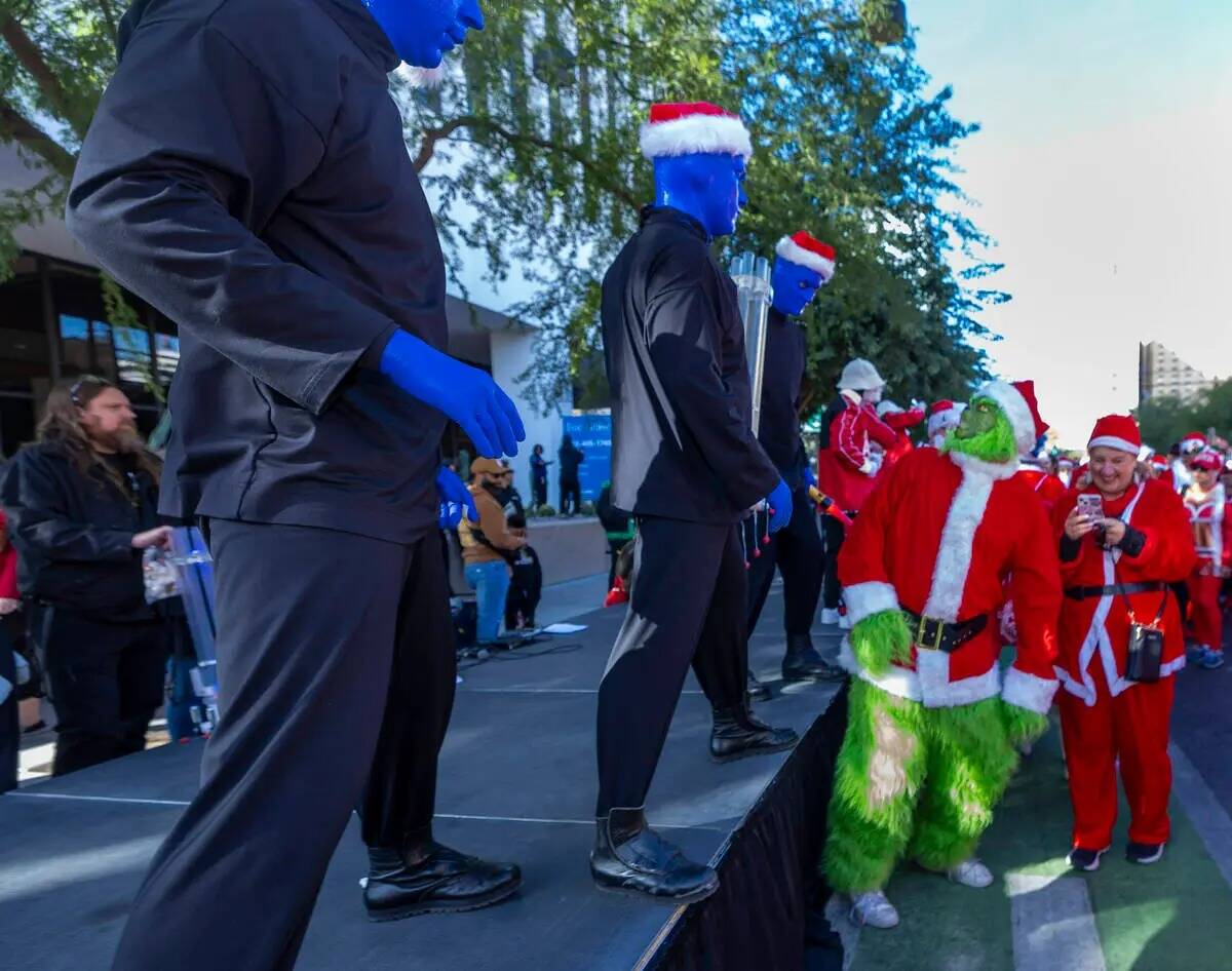 Un grinch observa al Blue Man Group en la fila de salida durante la Great Santa Run por el cent ...