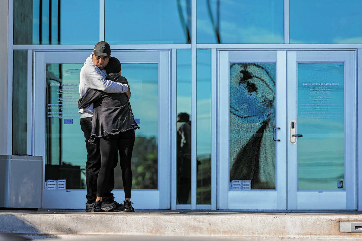 Dos personas se abrazan cerca de un panel de vidrio destrozado de la puerta delantera de la Uni ...
