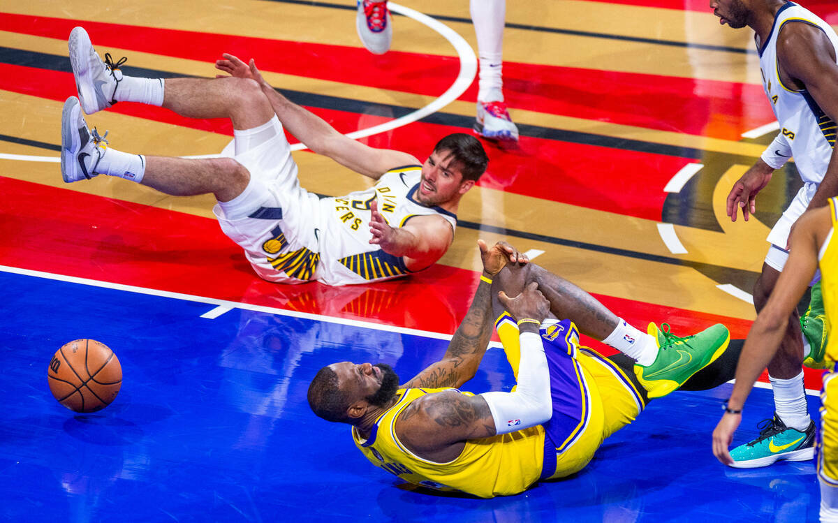 El alero de Los Angeles Lakers LeBron James (23) se agarra la rodilla tras un choque con el esc ...