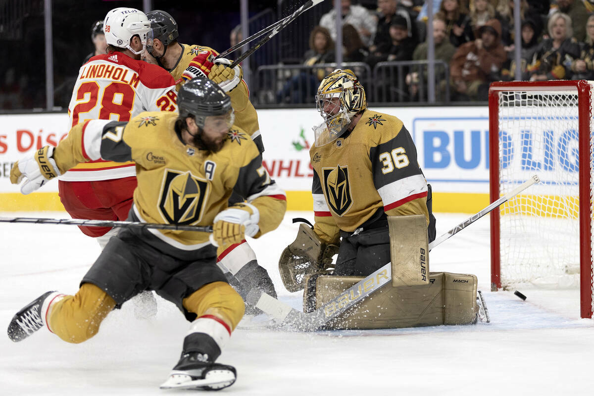 El centro de los Flames Elias Lindholm (28) asiste un gol mientras que el portero de los Golden ...