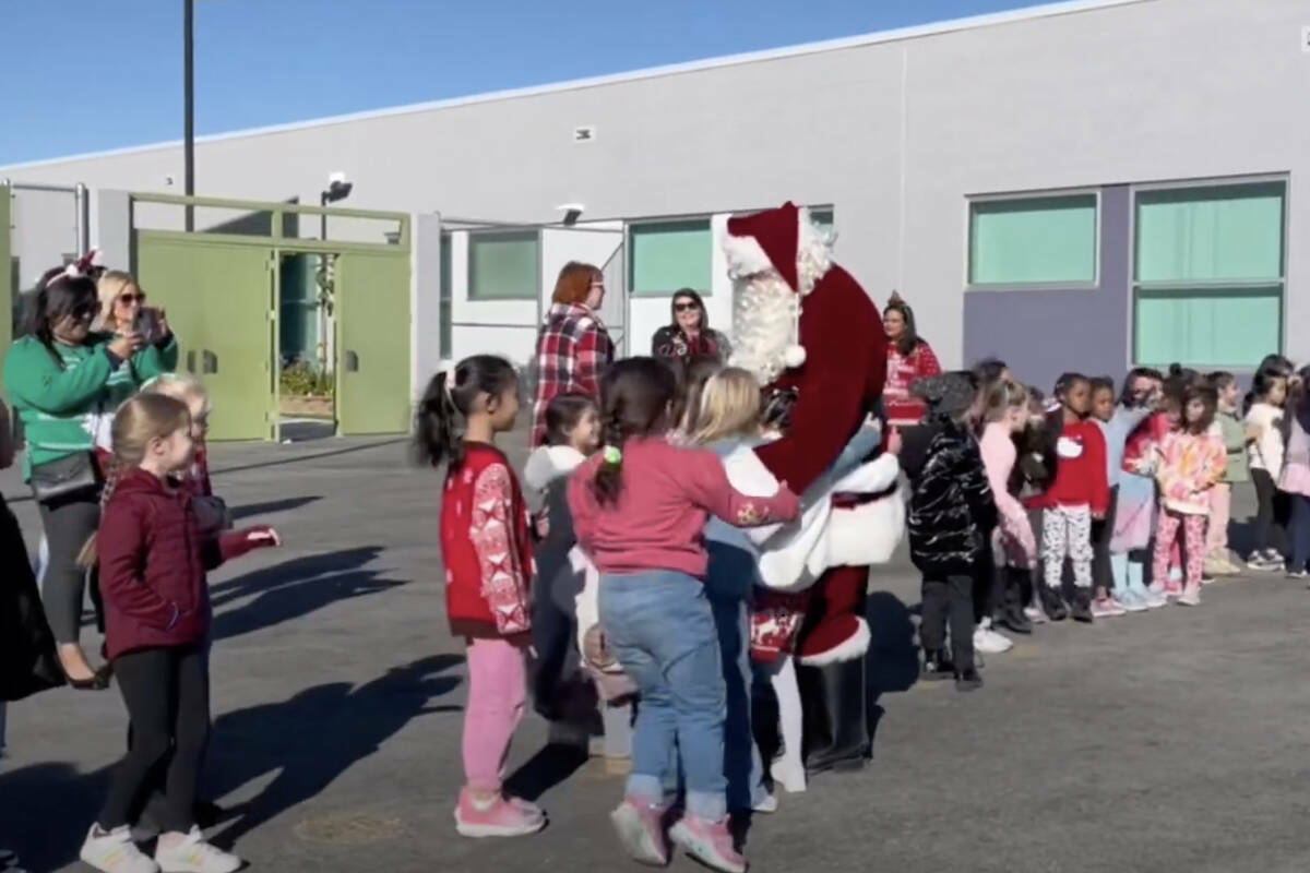Esta captura de pantalla de video muestra a Santa Claus distribuyendo juguetes a los estudiante ...