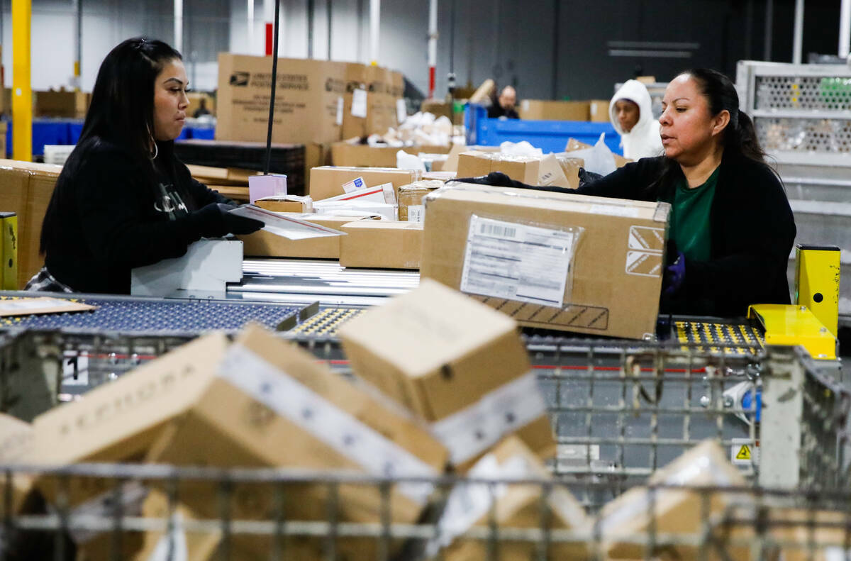 Kim López, izquierda, y Aureoia García, empleadas de USPS, clasifican paquetes en un centro d ...