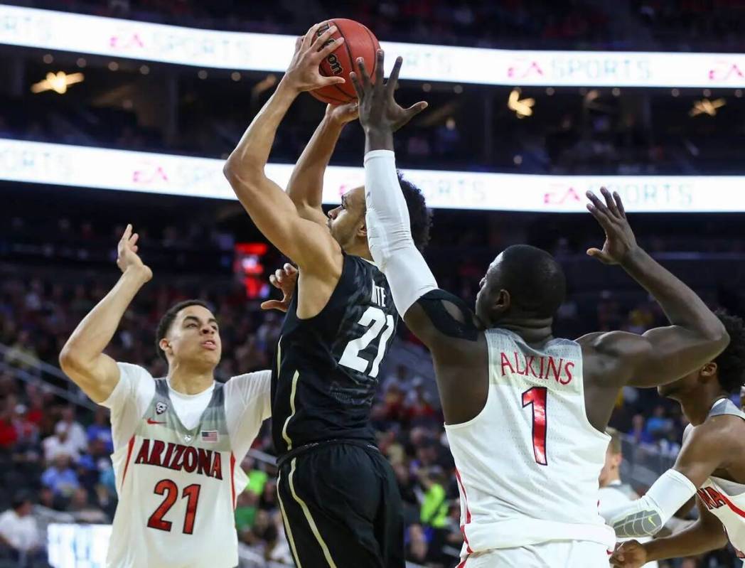 El escolta de Colorado Derrick White (21) conduce hacia la canasta entre el pívot de Arizona C ...