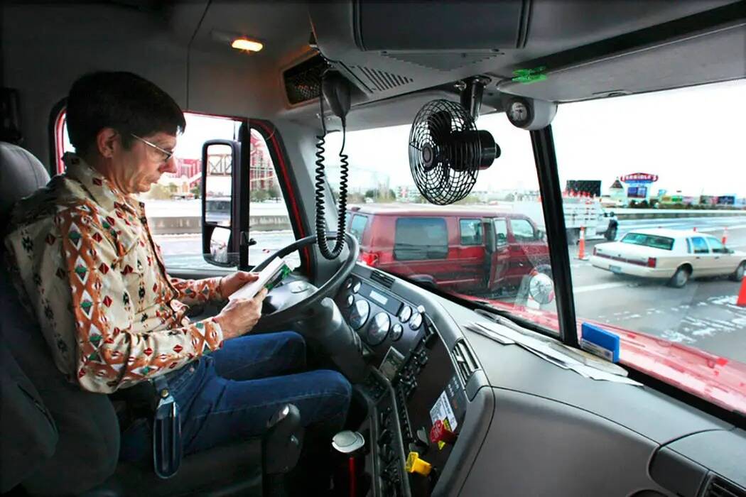 El conductor de un camión tractor Gary Mott se pone al día con su lectura en la Interestatal ...