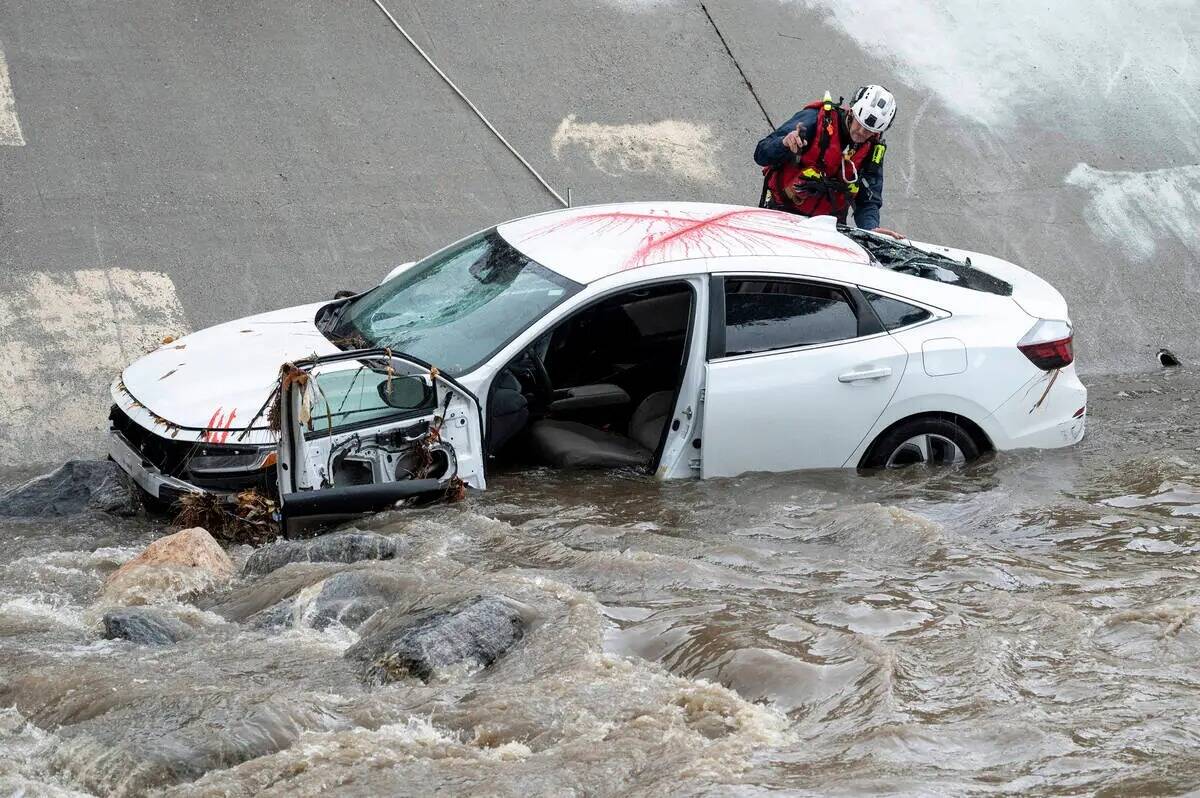 La policía, los bomberos y el personal de rescate de aguas rápidas responden a un auto en el ...