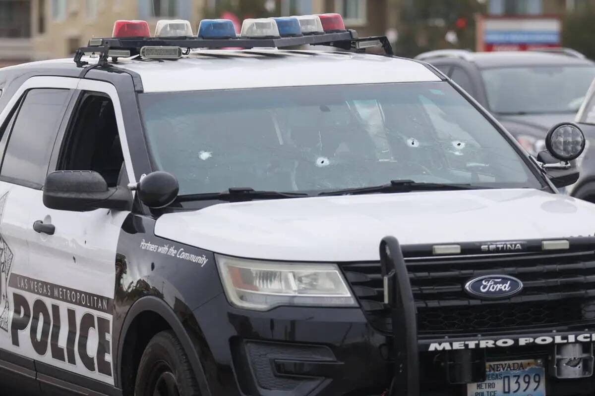 Un auto de policía con agujeros de bala en la escena de un tiroteo con participación de ofici ...
