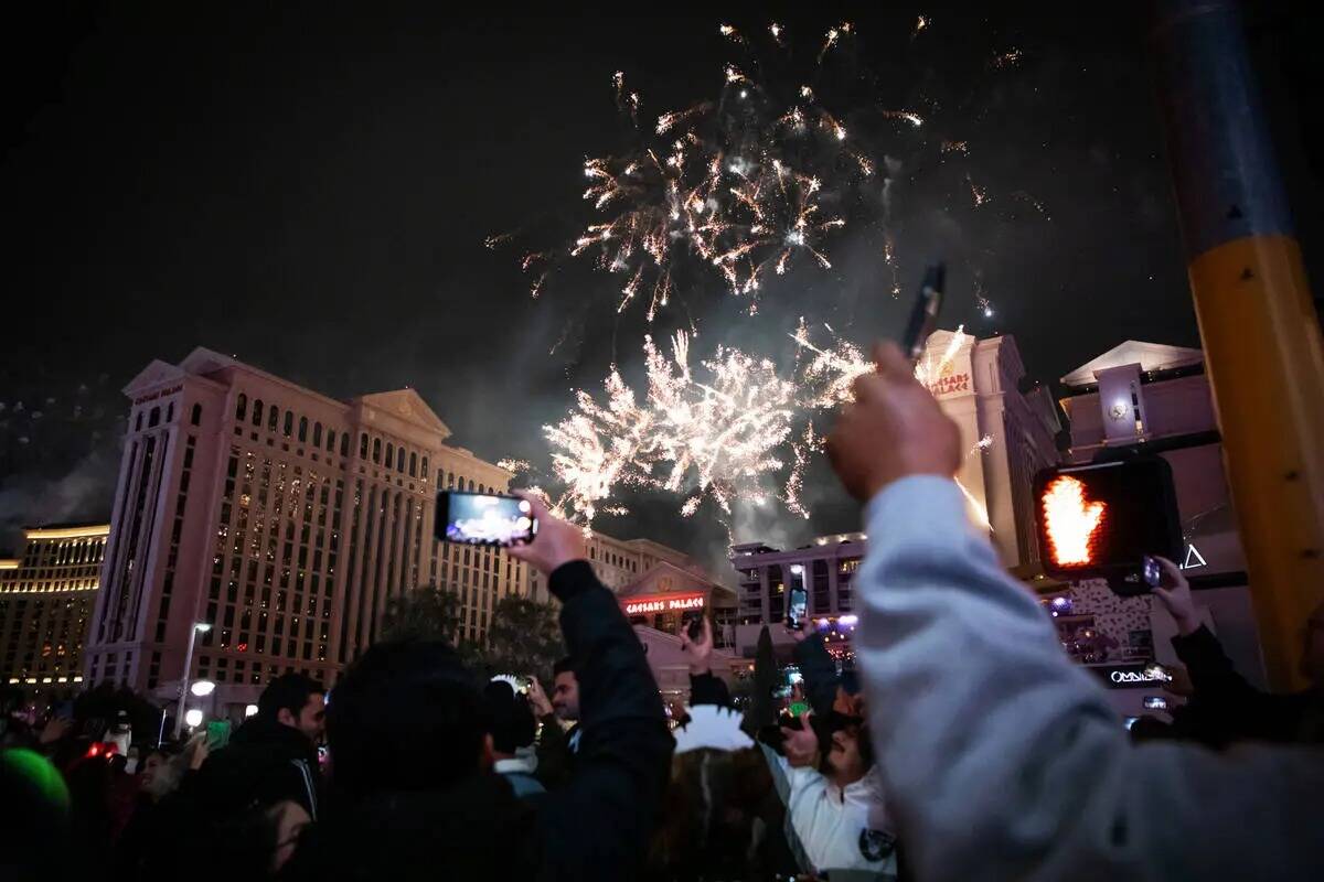 Fiesteros de Año Nuevo toman fotos y ven los fuegos artificiales en el Strip el domingo, 1 de ...