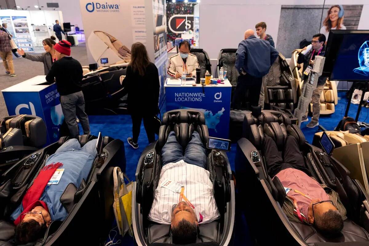 Los asistentes se relajan en los sillones de masaje Daiwa en el stand de la empresa durante la ...