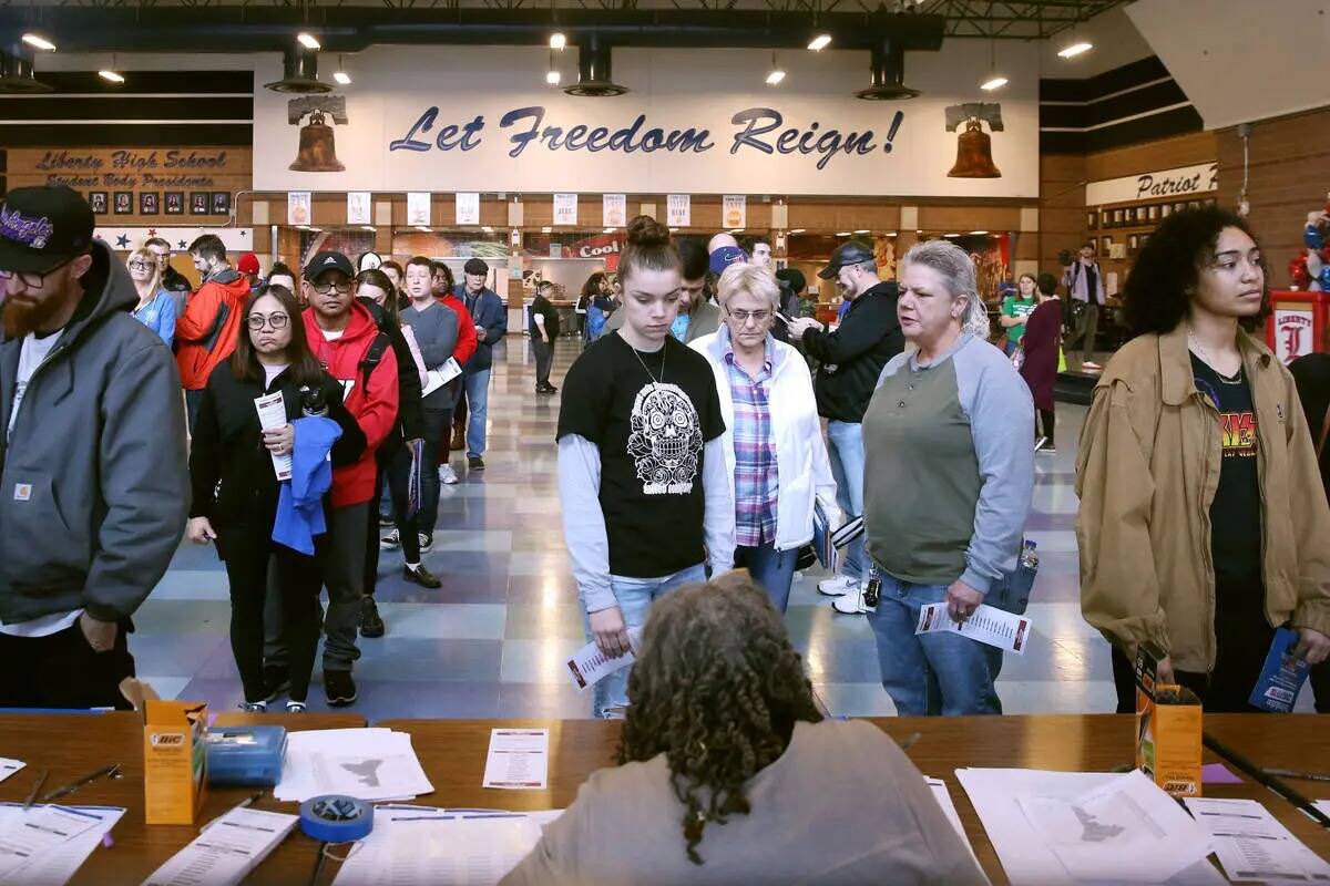 Los asistentes al caucus demócrata firman en el sitio del caucus en Liberty High School el sá ...