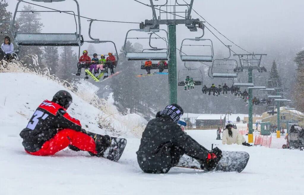 Los esquiadores y snowboarders usan el remonte para principiantes y la colina en la estación d ...