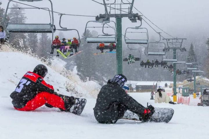 Los esquiadores y snowboarders usan el remonte para principiantes y la colina en la estación d ...