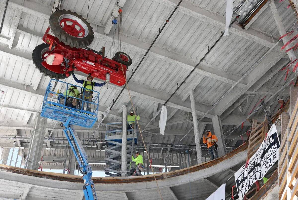 Trabajadores levantan un tractor antiguo para instalarlo en el techo del club de música en con ...