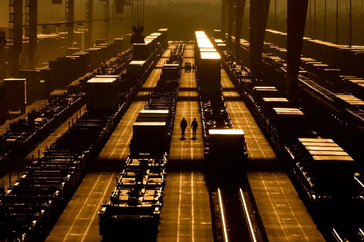 Trabajadores caminan entre contenedores de transporte en una terminal intermodal de BNSF, el mi ...