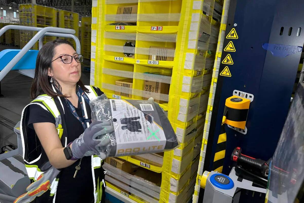 Un trabajador mueve un paquete en un centro de envío de entregas en el mismo día de Amazon en ...