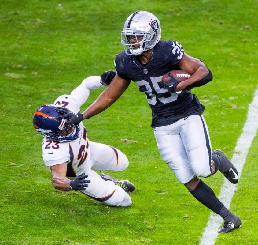 El running back de los Raiders Zamir White (35) arma al cornerback de los Denver Broncos Fabian ...