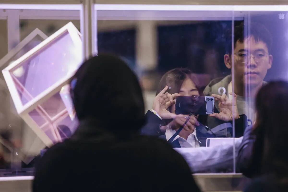 Una persona toma una fotografía del interior de un stand durante CES Unveiled en el Mandalay B ...