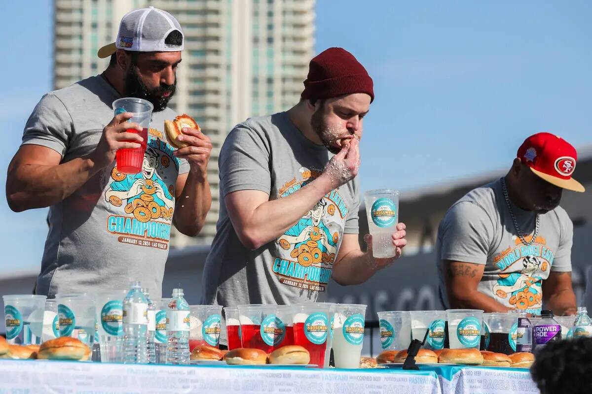 James Webb, a la izquierda, y Patrick Bertoletti compiten por comer tantos bagels con crema de ...