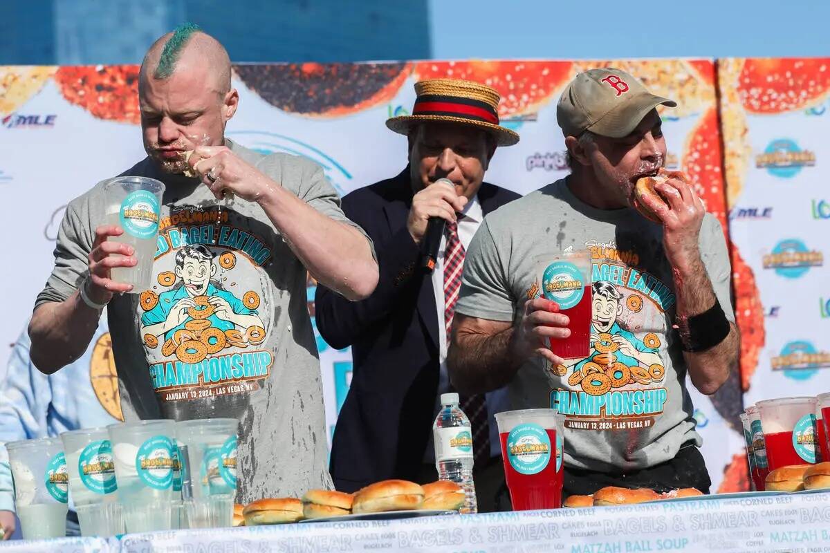 Nick Wehry, a la izquierda, y Geoff Esper compiten por comer tantos bagels con crema de queso c ...