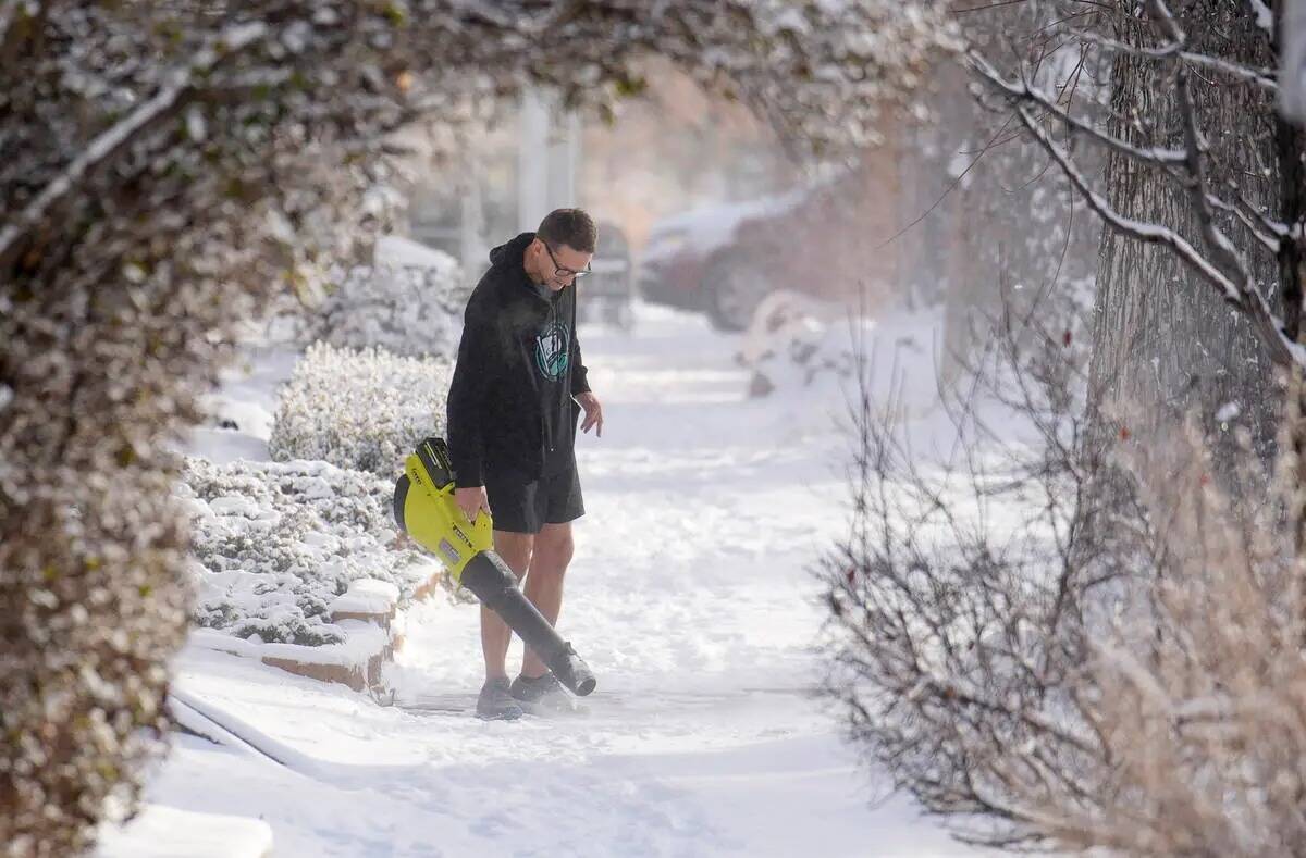 Con la temperatura máxima diurna muy por debajo de cero, un hombre usa un soplador de hojas pa ...