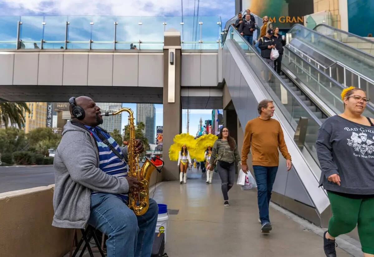 Un saxofonista toca cerca del puente peatonal que lleva al MGM mientras otras personas pasan ca ...
