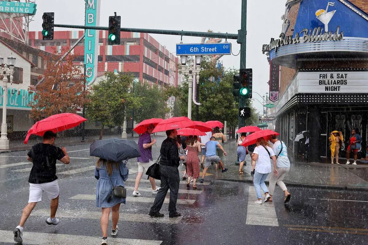 Un grupo de turistas hace frente a la lluvia en East Fremont Street, en el centro de Las Vegas, ...