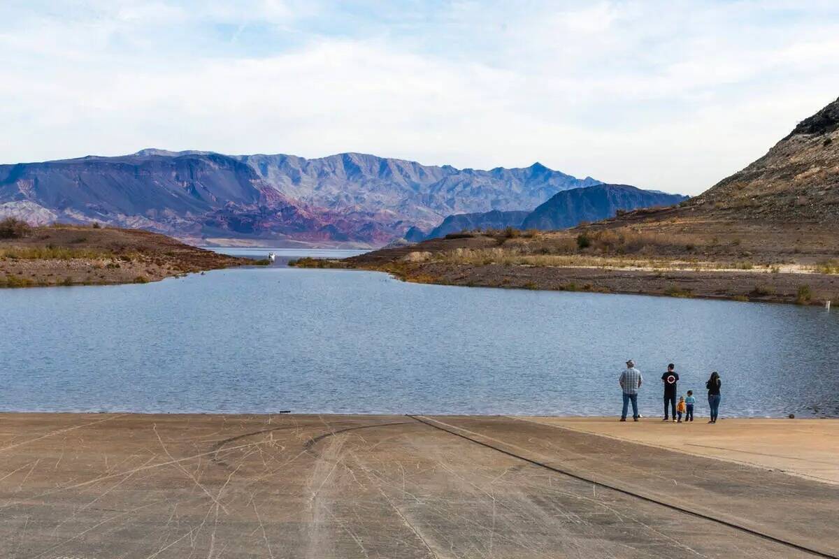 Los visitantes se paran en la orilla mientras el agua fluye de nuevo en Boulder Harbor después ...