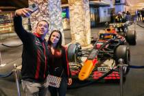 Turistas del Strip posan para una foto delante de un auto de Fórmula Uno de Red Bull Racing an ...