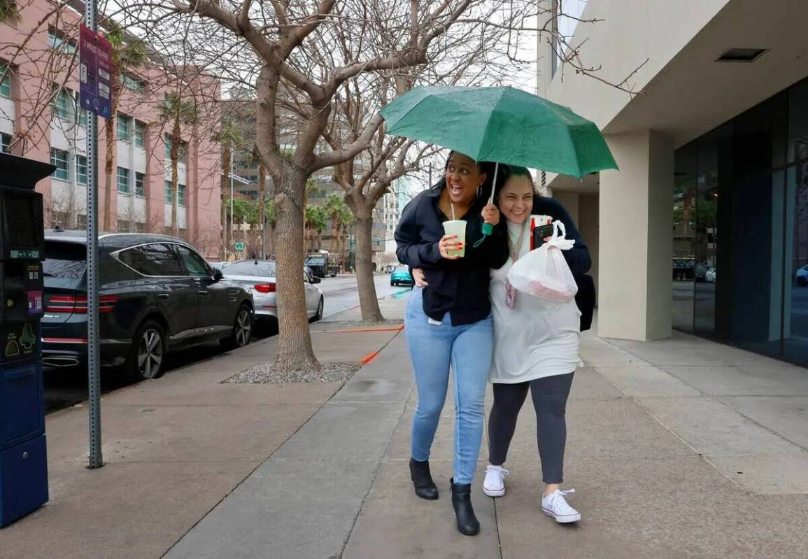 Nadia Williams, a la izquierda, y Julie Agrait desafían el viento y la lluvia mientras se abre ...