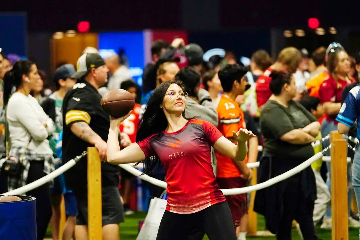 Un participante lanza un balón de fútbol americano en una exhibición de pases en la Super Bo ...