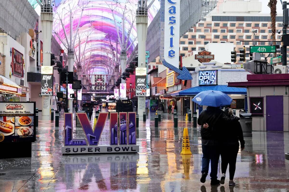 La gente camina bajo una ligera lluvia frente a una instalación del Super Bowl 2024 en el Frem ...