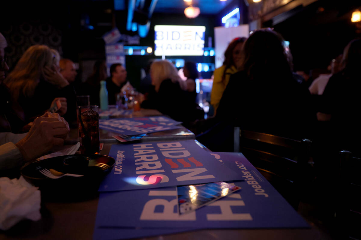 Carteles de la campaña Biden-Harris llenan las mesas durante una celebración después de que ...