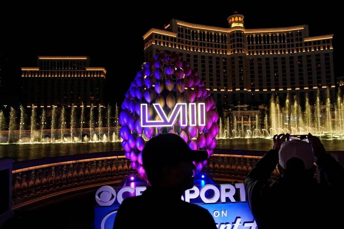 La gente se para junto a la señalización del Super Bowl mientras las fuentes del Bellagio est ...