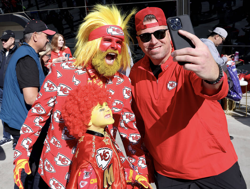 Un fanático de los Chiefs posa con Rick Draper y su hijo Hoyt Draper, de 8 años, afuera del A ...