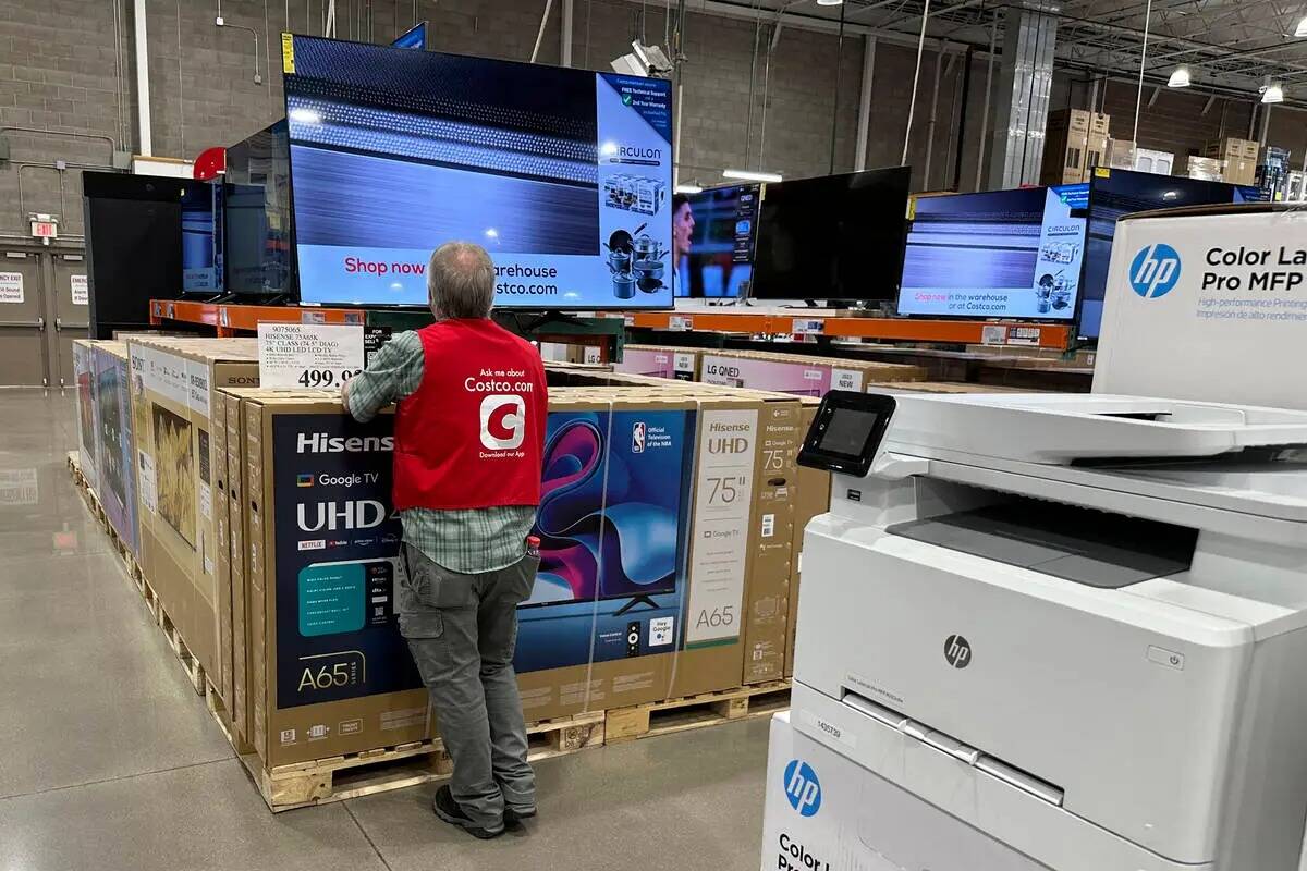 Un asociado revisa un televisor de pantalla grande en exhibición en un almacén de Costco, el ...