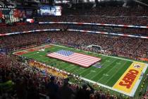 Una bandera de Estados Unidos se extiende sobre el campo antes del Super Bowl 58, el domingo 11 ...