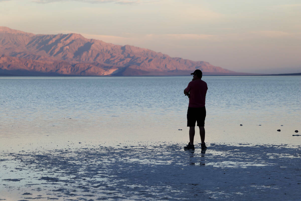 Un visitante observa un lago poco común en Badwater Basin, en el Death Valley National Park en ...