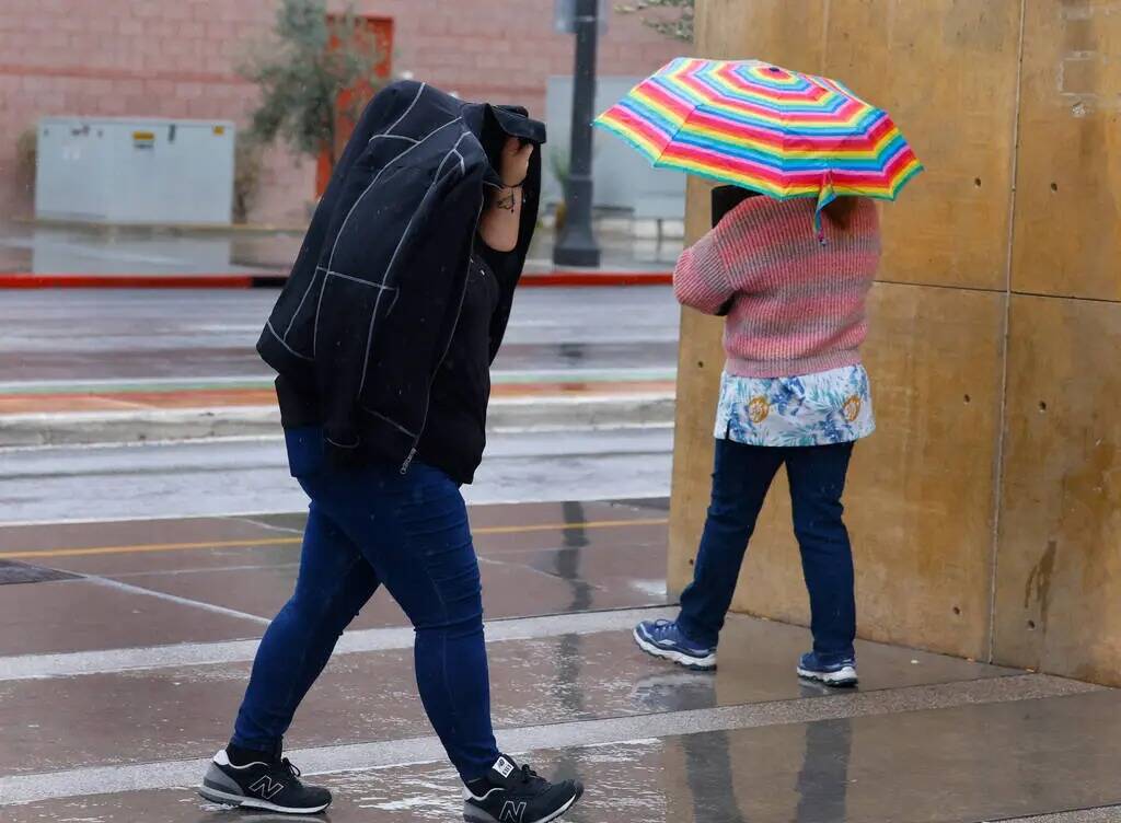 Peatones caminan por la Third Street durante una mañana lluviosa el martes 20 de febrero de 20 ...