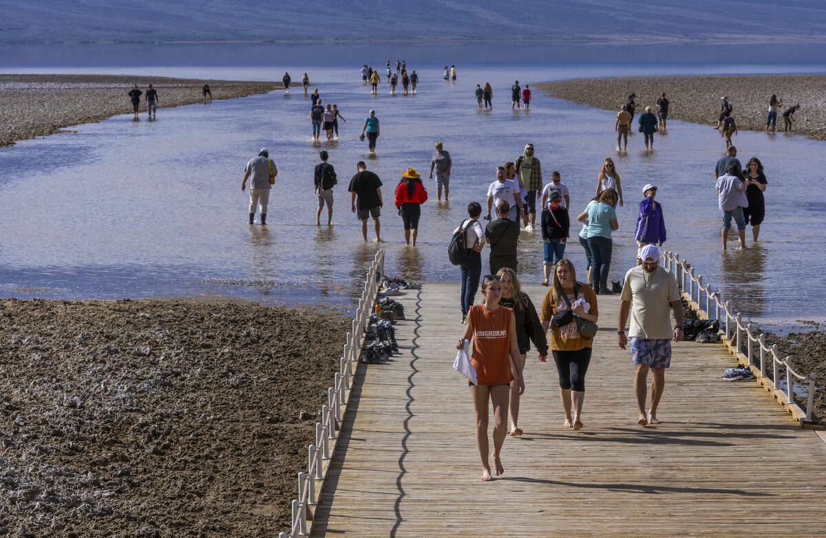 Personas entran y salen del agua en el lago temporal Manly en Badwater Basin, en el Death Valle ...