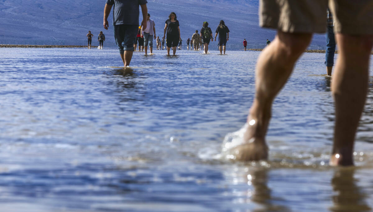 Personas entran y salen del agua en el lago temporal Manly en Badwater Basin, en el Death Valle ...